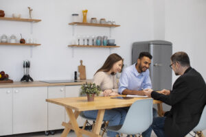 Homebuyers discussing property deal with realtor inside modern kitchen